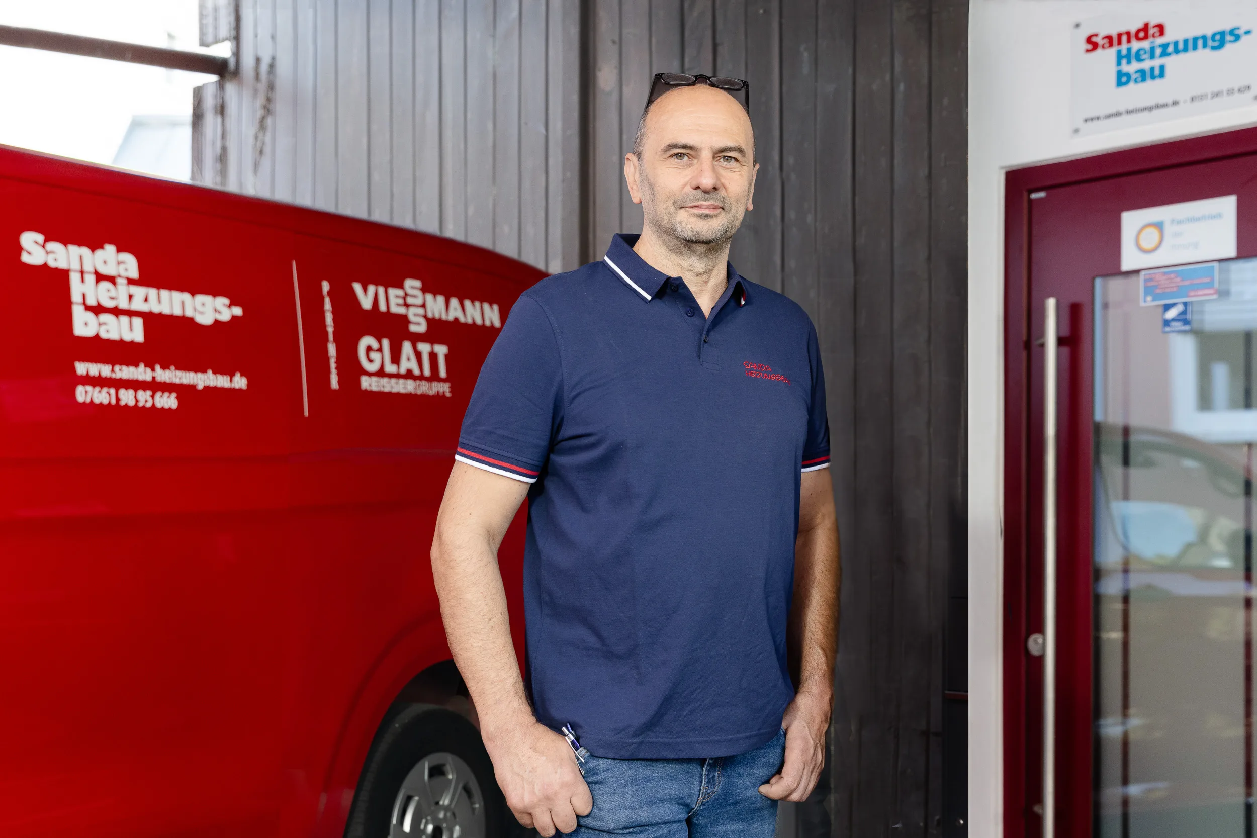 Silviu Sanda vor dem roten Servicefahrzeug mit Aufschrift Sanda Heizungsbau, Viessmann und Glatt Reissergruppe am Firmensitz in Kirchzarten.